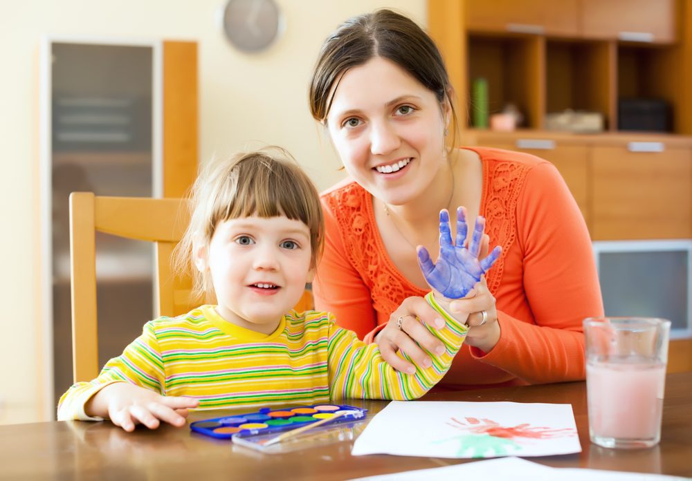 Child painting with a teacher